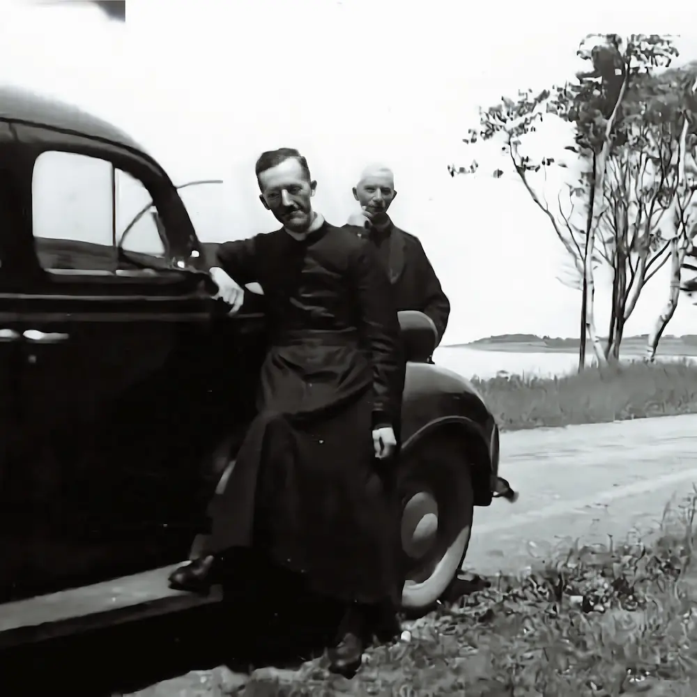 El padre Basile Babin y un compañero cerca de un automóvil antiguo